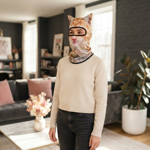 A smiling woman wearing a 3D cat face balaclava mask, captured in a bright, modern room with rose and charcoal decor.